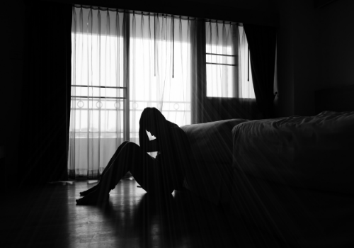 A man sitting in the dark and dealing with depression, needing Depression Treatment in East Peoria IL