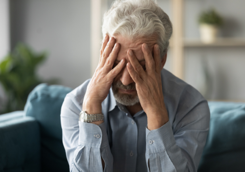An unhappy man holding his head while struggling with a Chronic Mental Illness in Peoria IL
