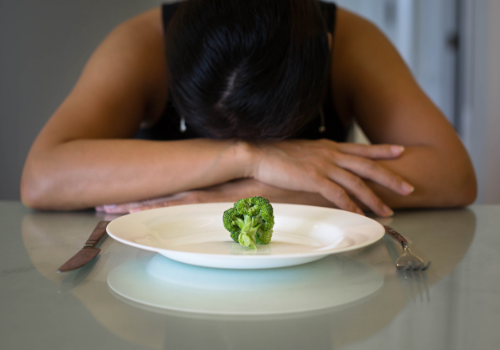 Frustrated woman only eating one piece of broccoli, suffering from Eating Disorders in Peoria IL