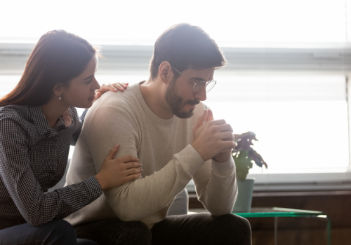 A woman comforting a man who is suffering from depression