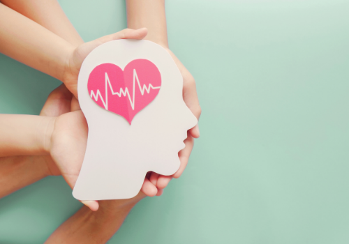 Hands holding a paper head with a heart, representing the work of a Therapist Near You
