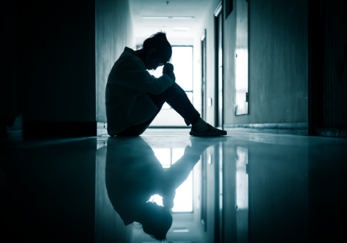 A sad woman sitting in a hallway in need of Grief Counseling in Peoria IL