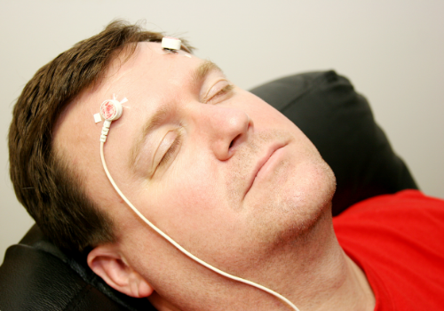 A man with his eyes closed and electrodes on his head, receiving Peoria Neurofeedback Treatment