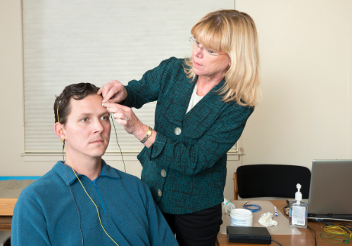 Woman attaching electrodes to a man's scalp during Peoria Neurofeedback
