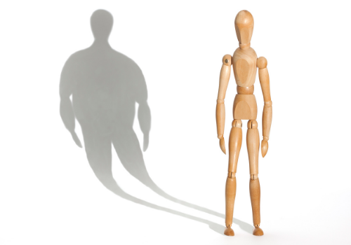 An image of a skinny person with a large shadow, how someone might think of their body when suffering from anorexia